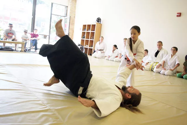 Marion Sconawah, 7, does a throw on James Landry at the Aiki Institute of Spokane. "Amazing stuff happens on the mat," says Landry. - YOUNG KWAK