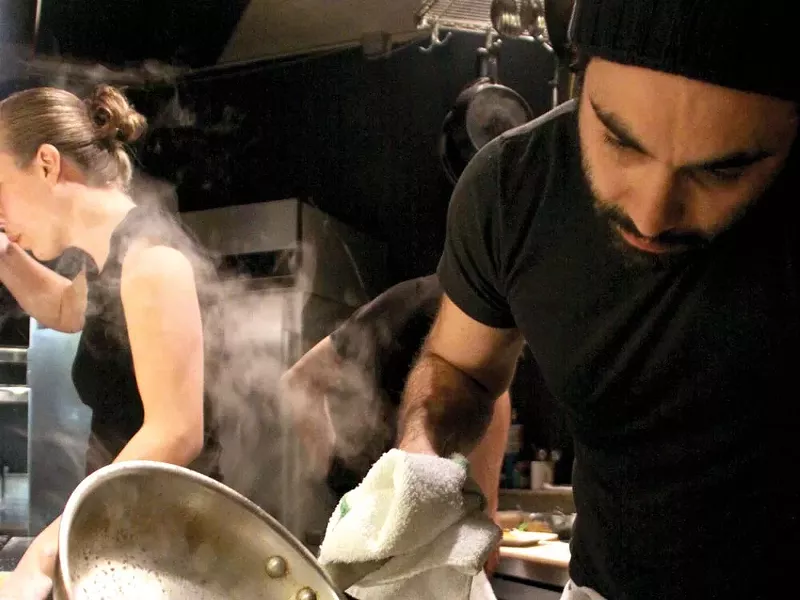 Nick Pitsilionis adds the final touches to an applewood-grilled pork loin - JOE PFLUEGER