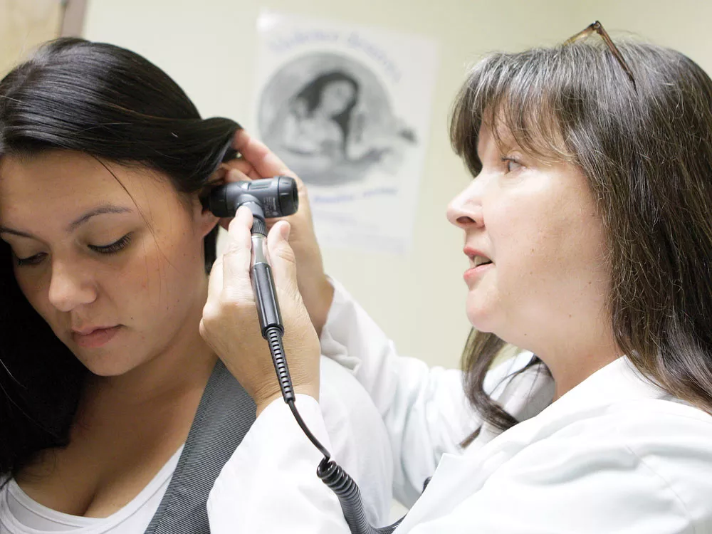 Nurse Vinetta MacPherson (left) demonstrates a medical exam on fellow employee Dezerae Hays at NATIVE Health of Spokane. - YOUNG KWAK