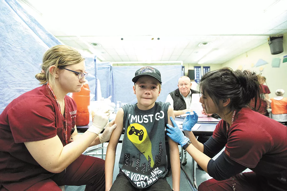 Nursing students immunize 11-year-old James Port during a free vaccine clinic organized by the Spokane Regional Health District. - YOUNG KWAK