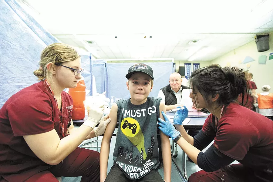 Nursing students immunize 11-year-old James Port during a free vaccine clinic organized by the Spokane Regional Health District. - YOUNG KWAK