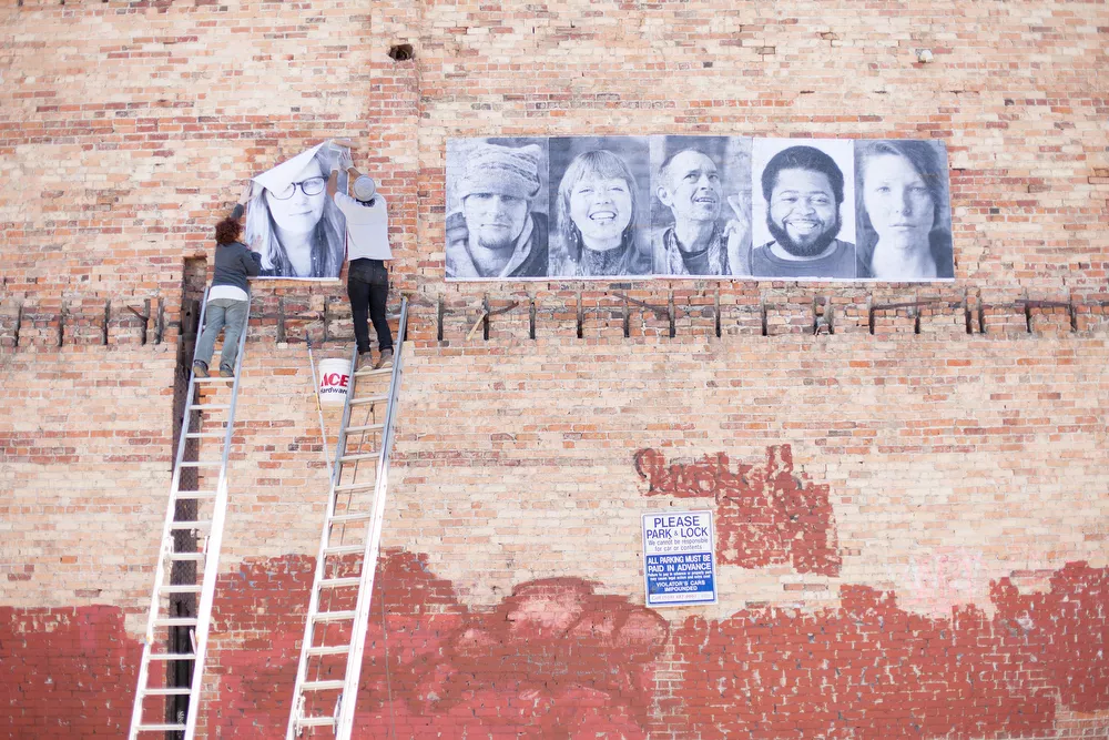 Organizer Susan Jane Hall, left, and volunteer Jose Villa paste a photograph of Laura onto a wall. - YOUNG KWAK