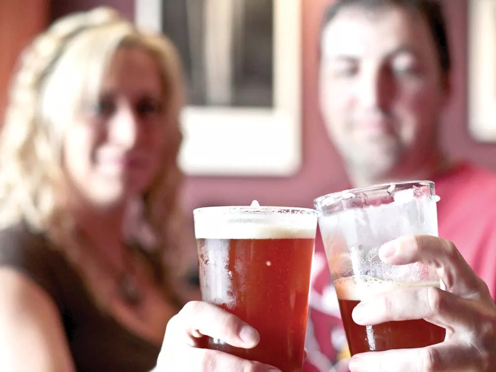 Owner Zeke Sawyer and employee Crysta Hyatt toast before sampling a local IPA at Bag o' Nails Pub. - JORDAN BEAUCHAMP