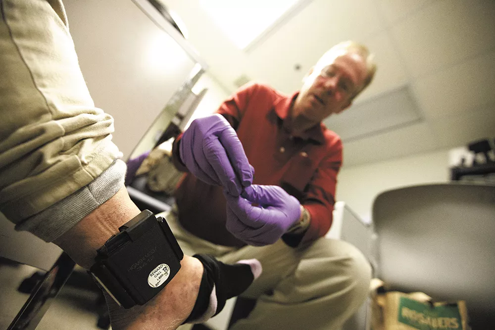 Probation Officer Mike Rafferty installs a transmitter on an unidentified female offender. - YOUNG KWAK