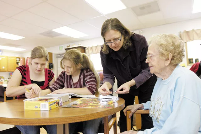 Renee Rinderknecht helps her 93-year-old mother, Dorothy Jensen, as her twin daughters do their homework at All Families Adult Day Care Center. - YOUNG KWAK