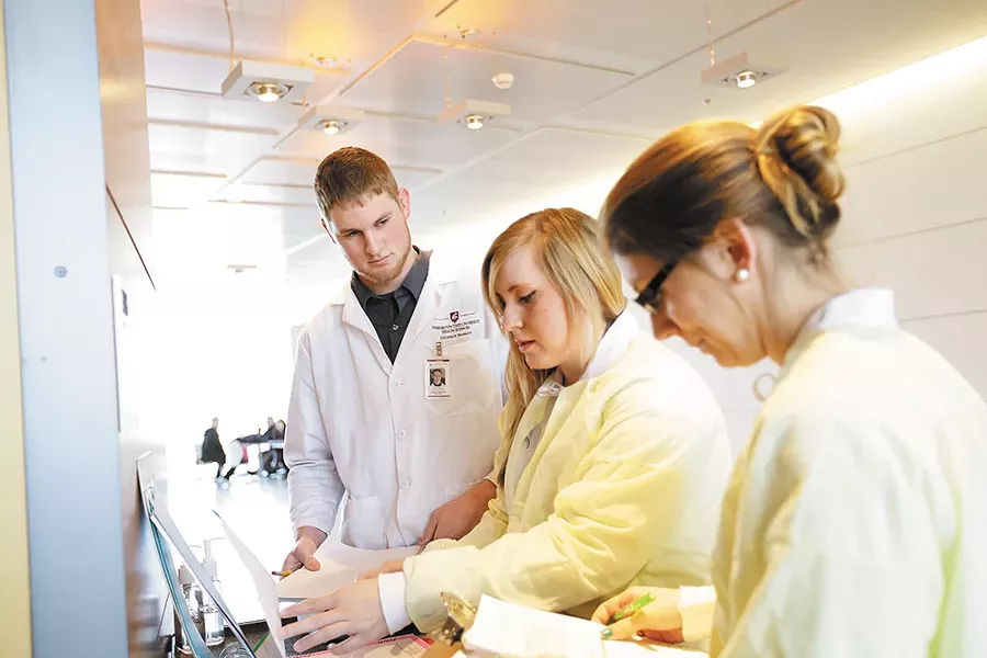 Second-year pharmacy students practice working closely with patients and as part of a team. Here, Kyle Roberts, Julie McCullough and Aubrie Widhalm review a patient chart before entering the simulation lab. - YOUNG KWAK