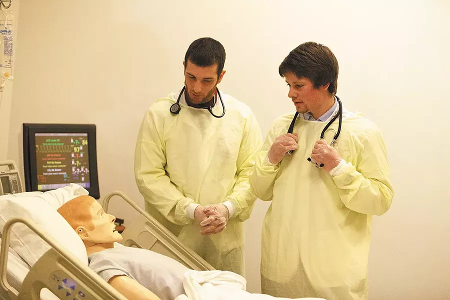 Second-year pharmacy students work in the simulation lab with a wirelessly operated, programmable mannequin, so realistic that its eyes blink and it can even cry or sweat. Here, Kyle Frazier and Taylor Bertsch interview their “patient.” - YOUNG KWAK