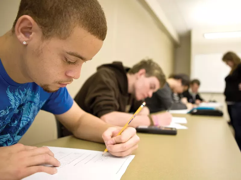 Student Isaiah Grant works on math problems in Math 114 at EWU. Professor Katie Campbell helps in the background. - STEPHEN SCHLANGE