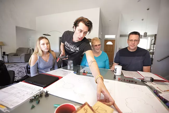 Dungeon master Josh Adrian, second from left, points out a spot on the game map to his sister Kayla (far left), grandmother Reggie Adrian and dad Joel Adrian. - YOUNG KWAK