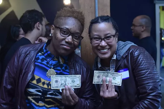 In an undated photo provided by the event organizer, Adia Gibbs, left, and Tina Valeria at a “Reparations Happy Hour” held in Portland, Ore. Organizers invited black, brown and indigenous people to a bar and handed them $10 bills a small but symbolic gift funded mostly by white people, who were asked not to attend. - CAMERON WHITTEN VIA THE NEW YORK TIMES