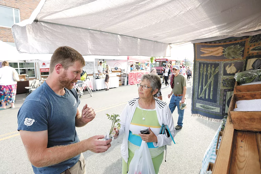 Woodard Family Farms owner Neil Woodard chats with a customer at the Kendall Yards Night Market. - YOUNG KWAK