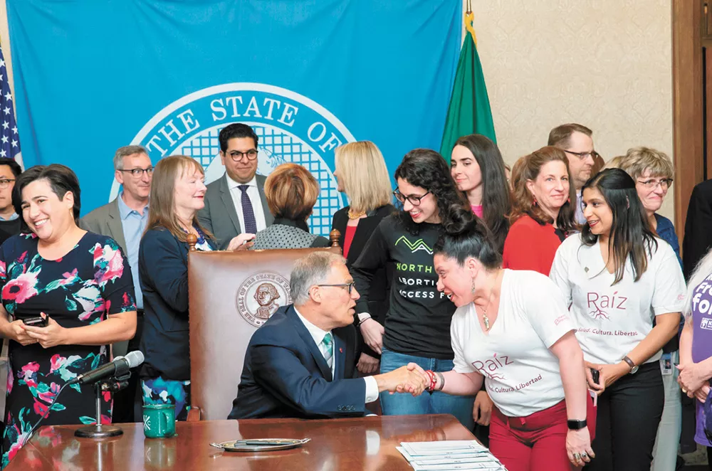 Lili Navarrete shakes Gov. Jay Inslee's hand at the Reproductive Health Access for All Act bill signing.