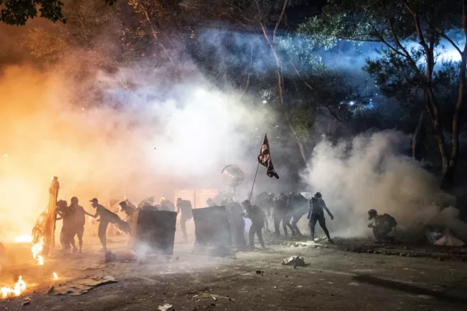 Protesters take cover behind makeshift shields at the Chinese University of Hong Kong in the Sha Tin district on Tuesday, Nov. 12, 2019. Antigovernment demonstrators angered by the shooting of a Hong Kong demonstrator fanned out across the city on Tuesday, blocking major transit arteries and staging a fiery standoff against riot police officers on the fringes of a university campus. - LAM YIK FEI/THE NEW YORK TIMES