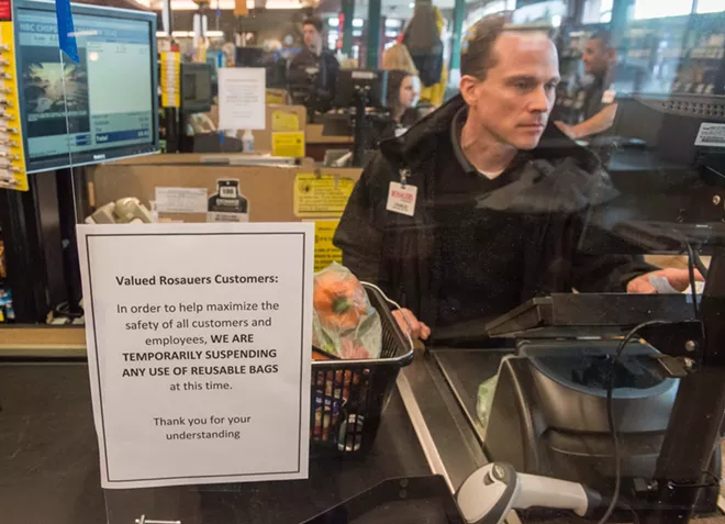 Plexiglas shields Rosauers clerks from sneezing customers, while a sign informs customers that they aren't allowed to bring their own reusable bags. - DANIEL WALTERS PHOTO