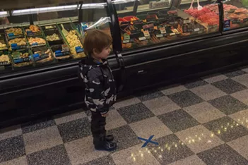 A very young shopper is enchanted to discover a social-distancing marking "X" has been placed at the meat counter at Rosauers. - DANIEL WALTERS PHOTO