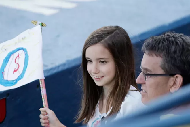 9 year old Eleanor Dinnig, left, holds a homemade Spokane Indians flag while sitting with her father Michael during the third inning. - YOUNG KWAK