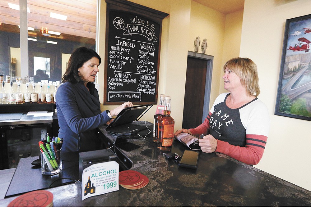Co-owner Mary Clemson (left) rings up customer Laurie Brown at Warrior Liquor. - YOUNG KWAK PHOTO