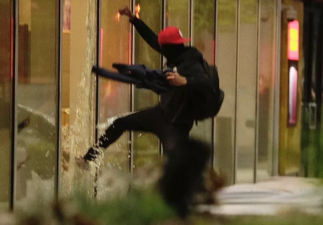 A man breaks a window at the Wells Fargo building on West First in downtown and is chased away by protesters. - YOUNG KWAK PHOTO