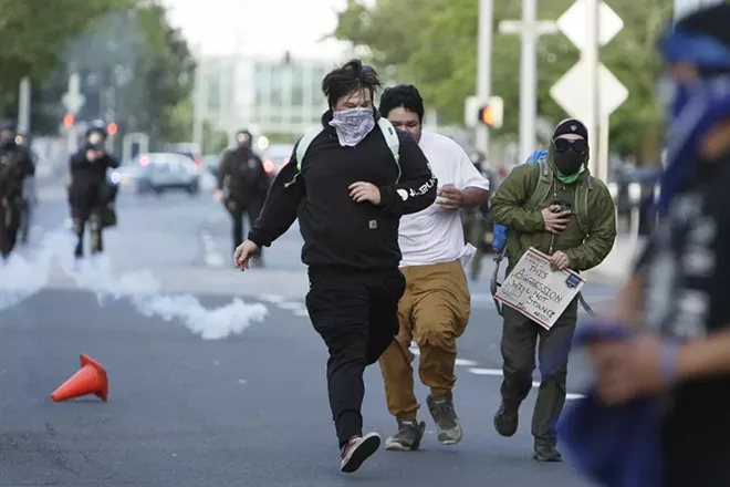 Demonstrators run as police deploy tear gas on W. Spokane Falls Blvd., in front of Riverfront Park. - YOUNG KWAK