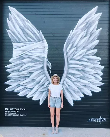 MiFlavour co-owner Ella Piskun stands in front of the bakery's new mural by artist Daniel Lopez. - MIFLAVOUR