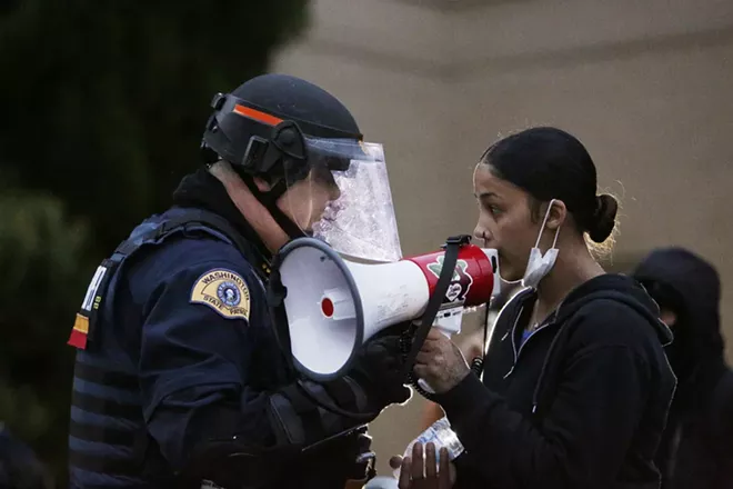 Washington State Patrol Lt. Kris Schweigert, left, speaks with Renee White to help keep the peace with one group of demonstrators in front of the Spokane County Public Works building during a recent protest. - YOUNG KWAK