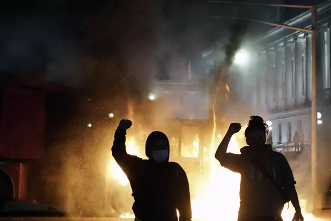 rotesters in front of a burning vehicle in Kenosha, Wis., on Monday night, Aug. 24, 2020, during a demonstration against the police shooting of Jacob Blake. Peaceful marches gave way to fires, destruction and looting in Kenosha as a strip of businesses in a central residential neighborhood was consumed in flames early Tuesday. - CARLOS JAVIER ORTIZ/THE NEW YORK TIMES