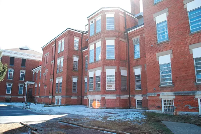 3-story red brick building on a sunny day with snow on the ground 