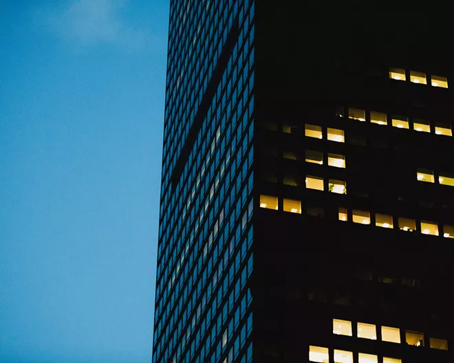 Lights glow at dusk in a few offices of a skyscraper in midtown Manhattan on May 4, 2020. With the coronavirus still surging in some parts of the country, a growing number of employers are delaying return-to-office dates once again, to the summer of 2021 at the earliest. - GEORGE ETHEREDGE/THE NEW YORK TIMES