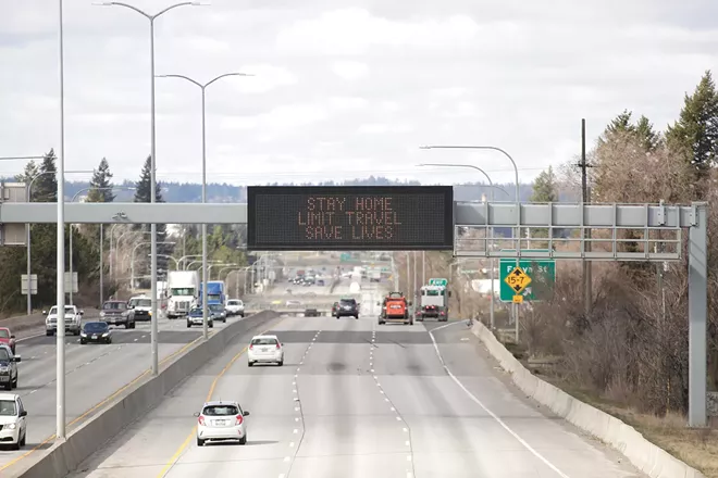 A sign stating "stay home, limit travel, save lives" is displayed over I-90 in Spokane last March. - YOUNG KWAK PHOTO