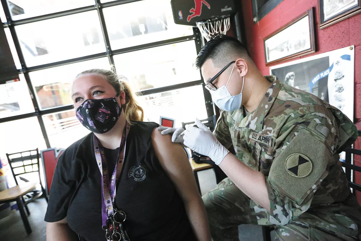 Washington Army National Guard Spc. Wendell Tu gives the COVID-19 vaccine to Miah Shirley during a clinic hosted by the Spokane Hospitality Coalition at David’s Pizza. - YOUNG KWAK PHOTO