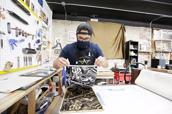 Reinaldo Gil Zambrano reveals a woodblock print of Monroe Street Bridge at the Spokane Print & Publishing Center. - YOUNG KWAK PHOTO