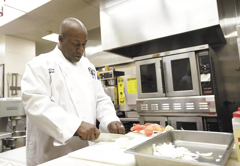 Derek Mobley preps onions for Union Gospel Mission's food service that feeds 5,000 every week. Mobley worked in the kitchen while getting clean. Now he's the boss. - YOUNG KWAK
