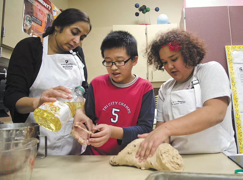 Tony and Napua learn breadmaking from volunteer Abtesam Khan at Pullman's Lincoln Middle School. - JACOB JONES