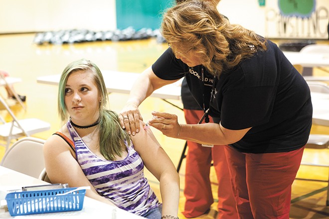 A student feels a pinch as she receives a vaccination at a clinic intended to get kids up to date on their immunization before school starts. - KRISTEN BLACK