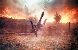 Gordon Maxwell dives over a fence as flames from Firestorm '91 rush towards him near Ponderosa in this award-winning photo by the late Kit King. Maxwell is a cook at a local restaurant. (Kit King / SR)