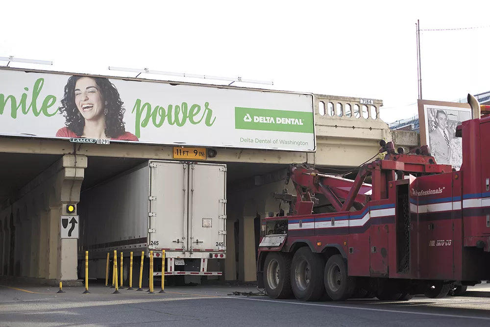 A truck, like several others this year, gets wedged underneath the railway bridge downtown, despite the sign warning of the low height. - YOUNG KWAK