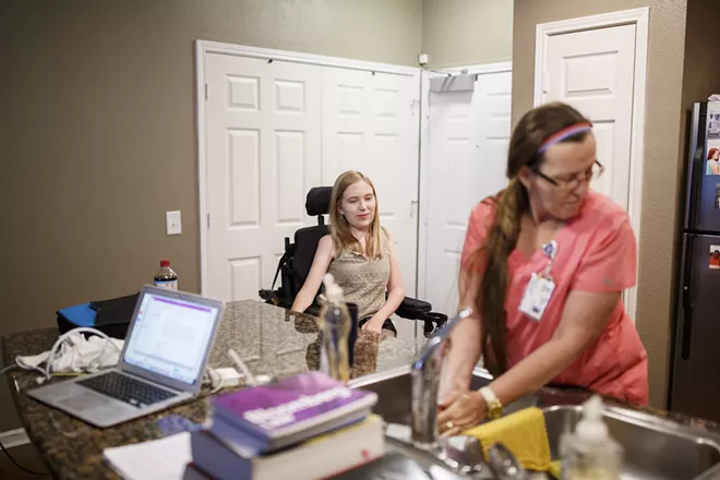 Frances Isbell looks on as personal care assistant Christy Robertson washes dishes and prepares food for her in Tuscaloosa, Ala., June 27, 2017. Isbell has spinal muscular atrophy and is finishing up law school at the University of Alabama. Optional benefits received by millions, many of them disabled, would be at risk under Republican proposals to repeal the Affordable Care Act. - MELISSA GOLDEN/THE NEW YORK TIMES