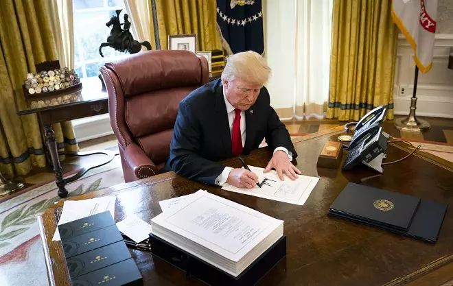 President Donald Trump signs a sweeping tax bill in the Oval Office of the White House, in Washington, Dec. 22, 2017. Trump signed the bill that Republicans promise will benefit the middle class, despite warnings from Democrats that the new law could be harmful to the country. - DOUG MILLS/THE NEW YORK TIMES