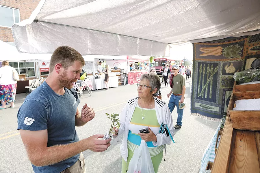 Woodard Family Farms owner Neil Woodard chats with a customer at the Kendall Yards Night Market. - YOUNG KWAK