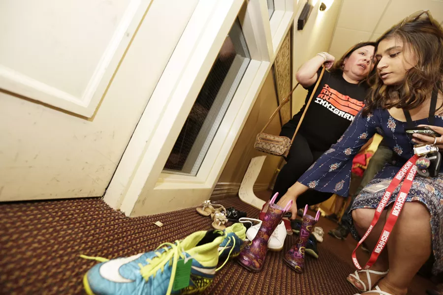 Sarah Dixit places shoes outside the office of Rep Cathy McMorris Rodgers as Lili Navarrete looks on, during an immigrant rights protest in Spokane, Thursday, July 5. - YOUNG KWAK