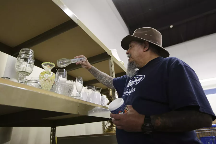 Randy Mora looks at a vase at a Goodwill store. - YOUNG KWAK