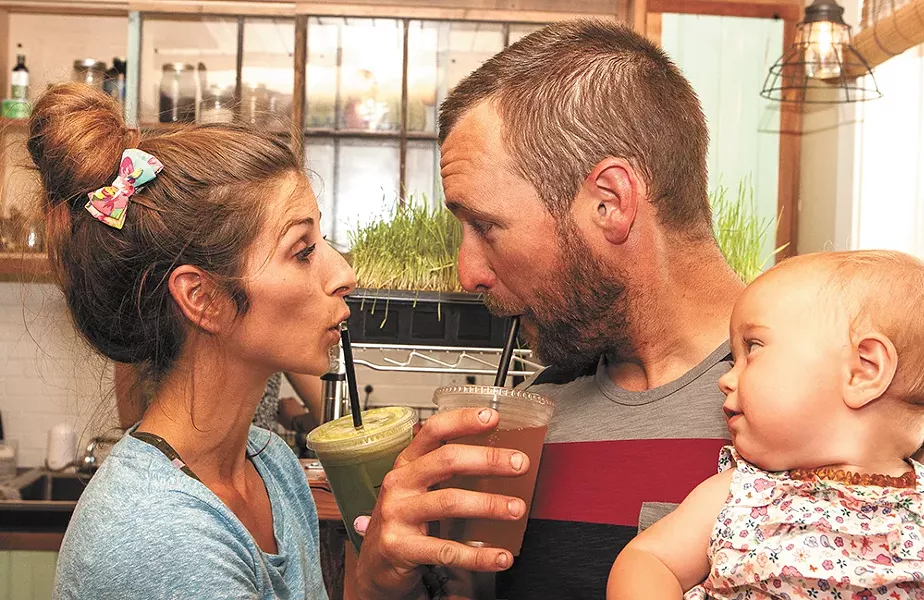 BIJA owner Brandi Elder (left) and John Gardner sip creations from BIJA Organic Juicery and Kombucha Bar as baby Nicoya looks on. - MEGHAN KIRK