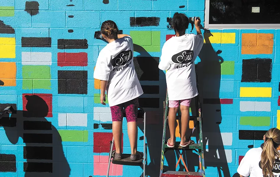 Gonzaga students paint a mural on a new nonprofit restaurant called Fresh Soul in the East Central neighborhood. The mural was designed by Spokane Arts Fund program manager Ellen Picken in collaboration with Spokane Arts, Fresh Soul and Gonzaga University. - RAJAH BOSE PHOTO