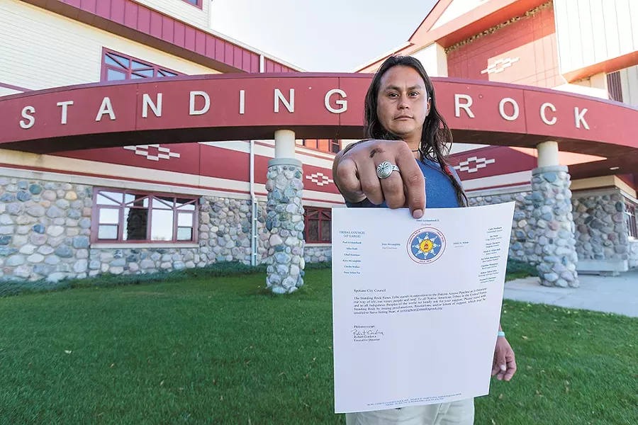 Jacob Johns, a Spokane resident and Gila River Pima tribal member, in front of the Standing Rock Sioux Tribe administration building, with a letter from the tribe asking the Spokane City Council to support efforts to stop construction of the pipeline. - JEFF FERGUSON
