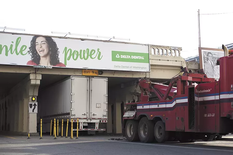A truck, like several others this year, gets wedged underneath the railway bridge downtown, despite the sign warning of the low height. - YOUNG KWAK