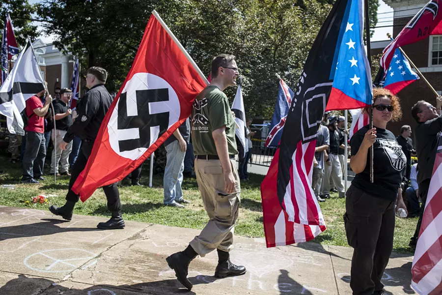 A white nationalist carries a Nazi flag during a protest in Charlottesville, Va., Aug. 12, 2017. The White House, under siege over President Trump’s initial comments, on Sunday condemned “white supremacists” for inciting violence that left a woman dead Saturday. - EDU BAYER/THE NEW YORK TIMES