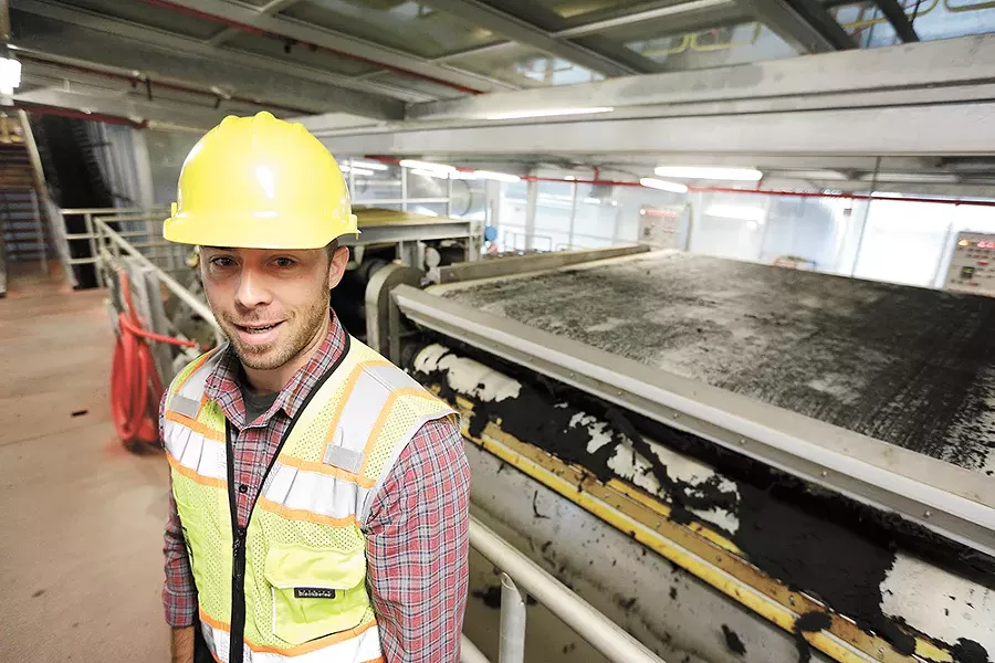 Kyle Arrington, a chemist with Spokane Wastewater Management, shows the press that removes excess water from biosolids. - YOUNG KWAK