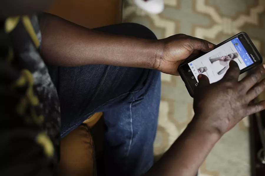 Michael Bacuth scrolls through photos of his 11 year old niece Nyabel Thok Pol on his phone at his home in Spokane. He and his wife Mary Chol, not pictured, came to the United States as refugees from South Sudan in 2006. They are currently trying to bring Pol, who is currently in Egypt, and is also a refugee from South Sudan, to the United States. Pol's parents were killed as they fled South Sudan. - YOUNG KWAK