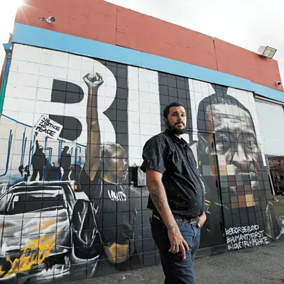 Local artist Daniel Lopez in front of his George Floyd mural.