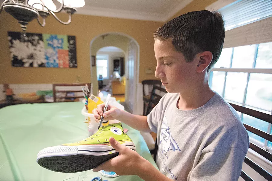 Volunteer Dylan Soth puts his creativity to work on a pair of Converse. - YOUNG KWAK